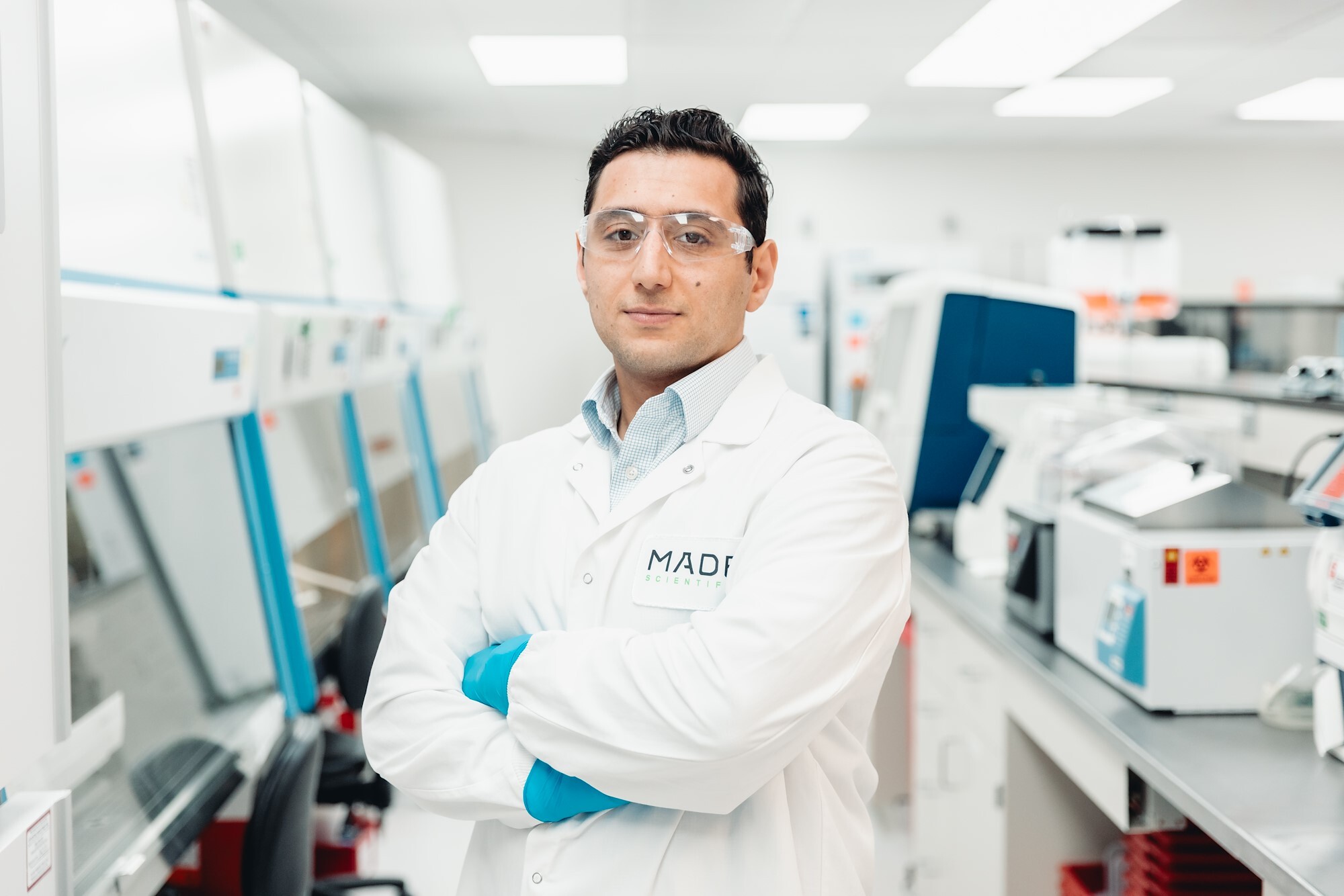 Scientist in a lab coat and safety glasses with arms crossed in the Made Scientific process development lab